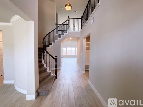 A spacious hallway with a staircase and a light on the ceiling.