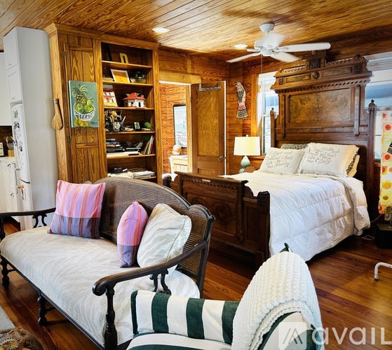A bedroom with a bed, a couch, and a wooden cabinet.