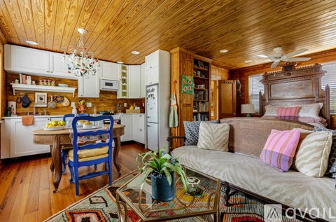 A bedroom with a bed, a couch, and a wooden cabinet.