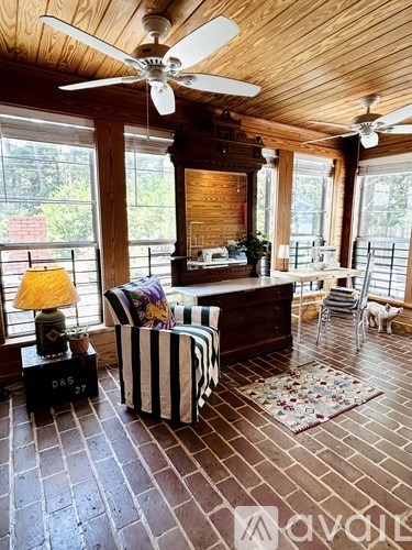 A living room with a striped chair and a ceiling fan.