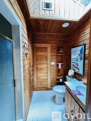 A bathroom with wooden walls and a toilet.
