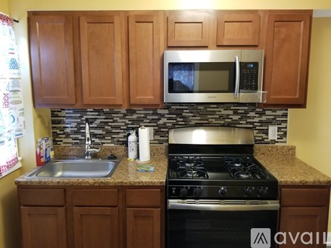 A kitchen with a stove, sink, and cabinets.