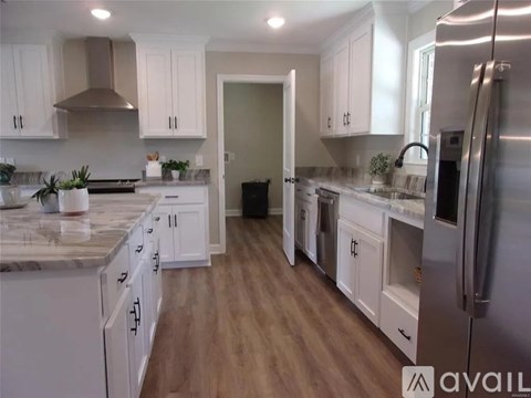 A kitchen with white cabinets and a marble countertop.