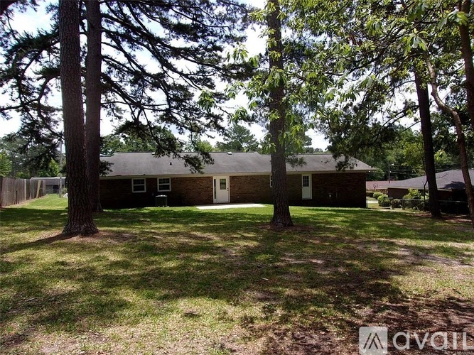A house with a brown roof and a white door is surrounded by trees.