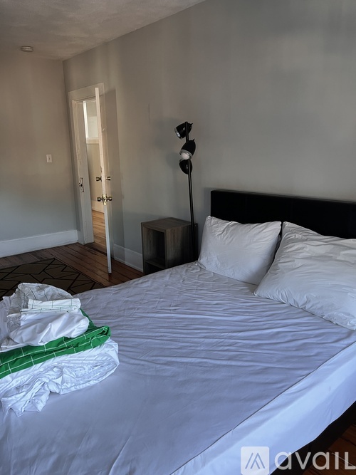 A bedroom with a white bed and a green blanket on it.