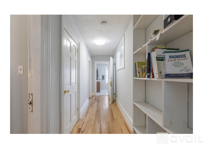 A hallway with a bookshelf on the right side.