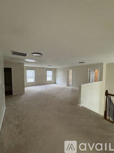 A spacious room with carpeted floor and a balcony with a railing.