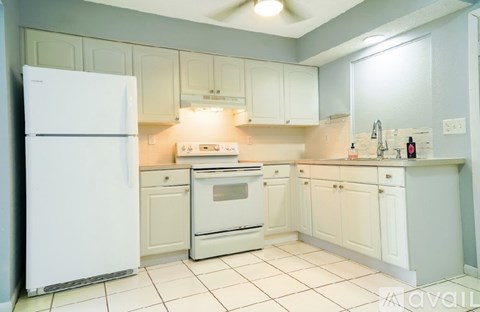 A white refrigerator is in a kitchen with white cabinets.