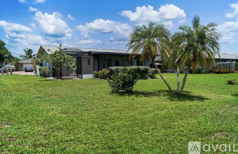 A grassy area with a building and palm trees in the background.