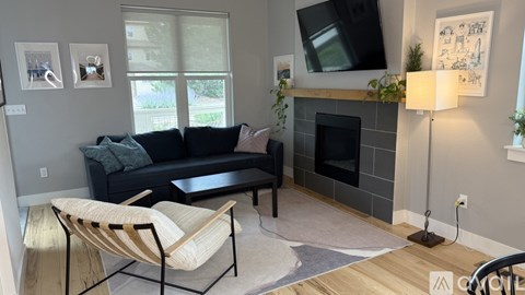 A living room with a black couch and a fireplace.
