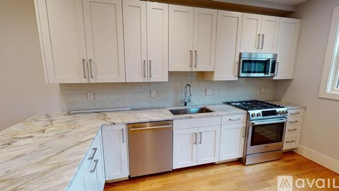 A kitchen with white cabinets and a marble countertop.
