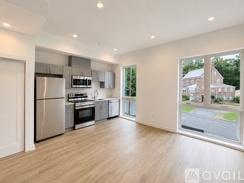 A modern kitchen with stainless steel appliances and wooden flooring.