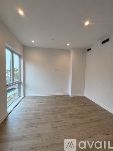 A spacious room with wooden flooring and a large window.
