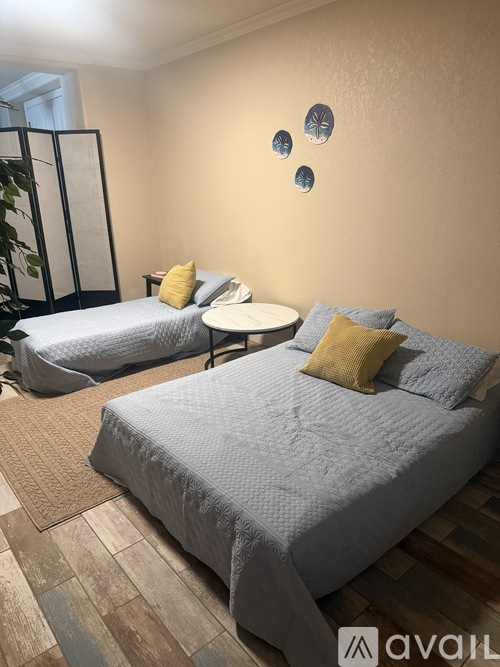 A bedroom with two beds and a small table.