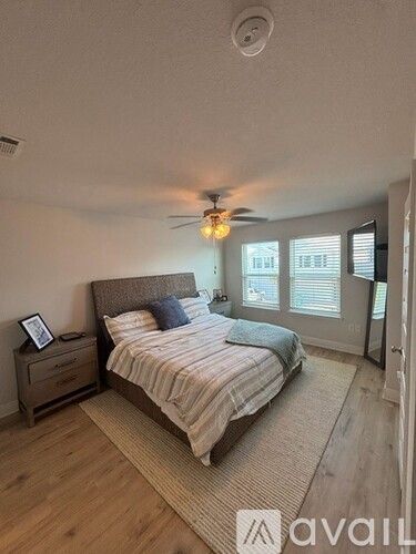 A bedroom with a bed, nightstand, and ceiling fan.