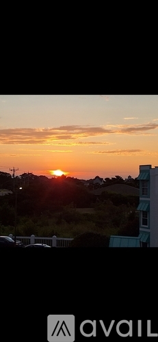 A sunset view from a balcony with the sun partially visible.