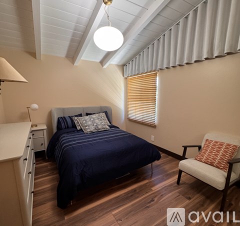 A bedroom with a bed, chair, and a window with blinds.