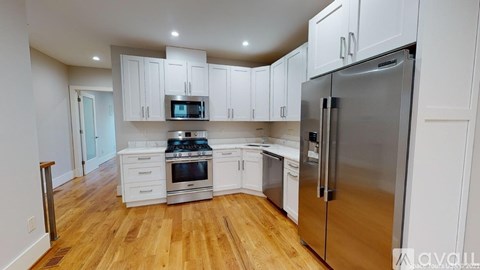 A kitchen with white cabinets and a wooden floor.