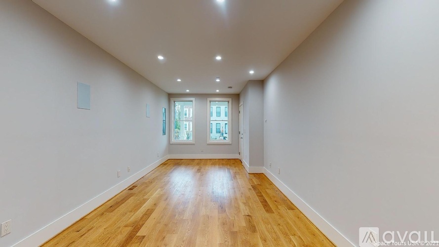 A spacious room with wooden flooring and a window.