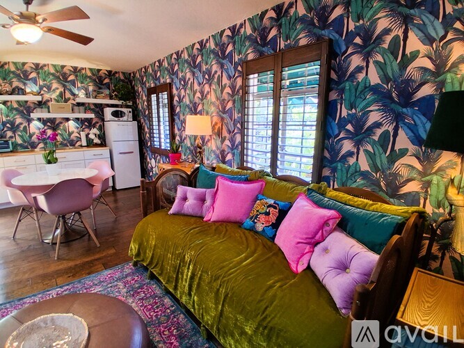 A bedroom with a bed, a dining table, and a ceiling fan.