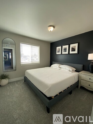 A bedroom with a bed, nightstand, and a round mirror on the wall.