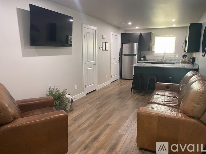 A living room with a brown leather couch and a wooden floor.