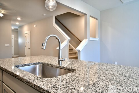 A kitchen with granite countertops and a stainless steel sink.