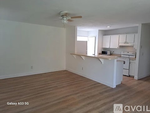 A kitchen with white cabinets and a wooden floor.