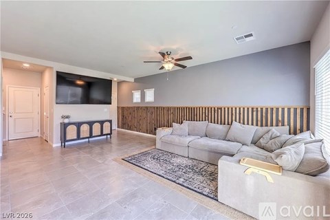 A living room with a grey couch and a wooden panel on the wall.