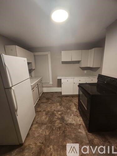 A kitchen with a white refrigerator and black countertops.