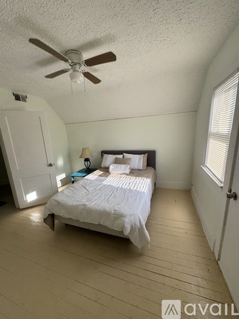 A bedroom with a bed, a ceiling fan, and a lamp.