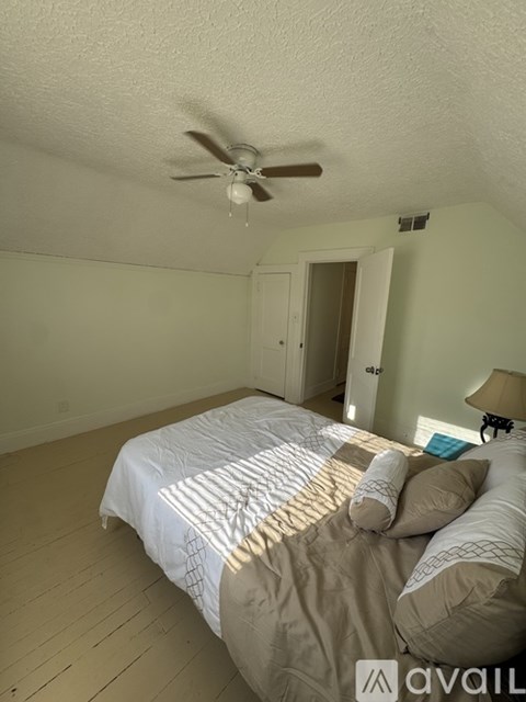 A bedroom with a bed, a ceiling fan, and a lamp.