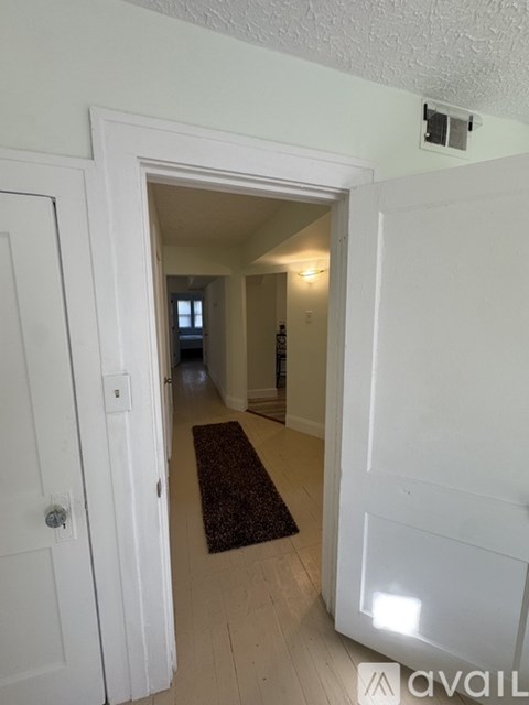 A hallway with a rug on the floor and a door on the left.