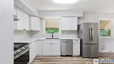 A kitchen with white cabinets and a stainless steel refrigerator.