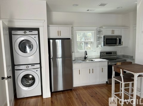 A white kitchen with a wooden floor and a table.