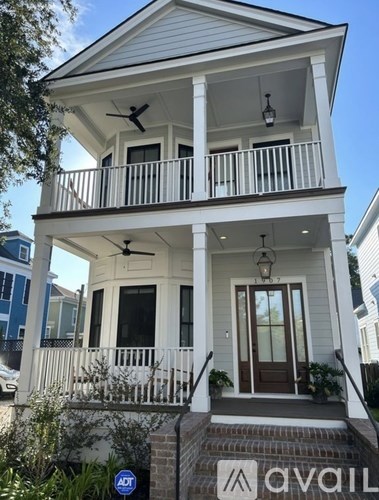 A white two-story house with a balcony and a door.