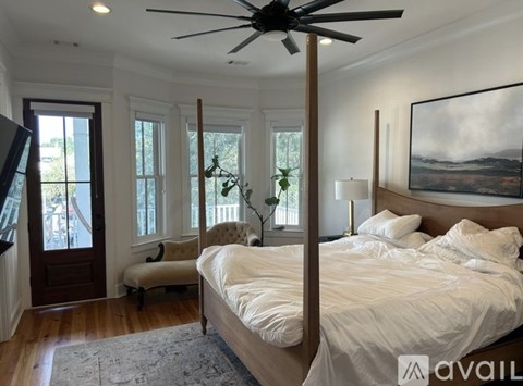 A bedroom with a large bed, a ceiling fan, and a painting on the wall.
