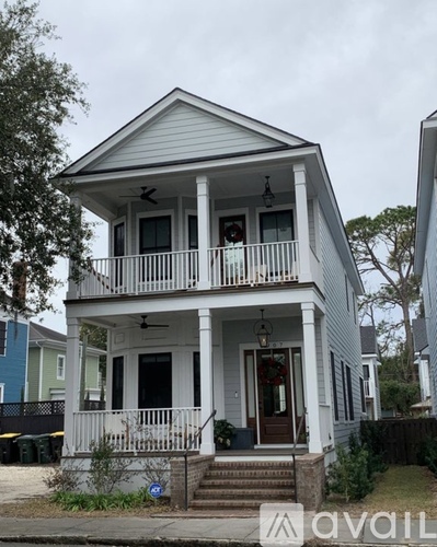 A white two-story house with a balcony and a front porch.