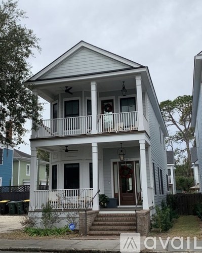 A white two-story house with a balcony and a front porch.