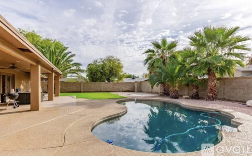 A pool surrounded by palm trees and a patio area.