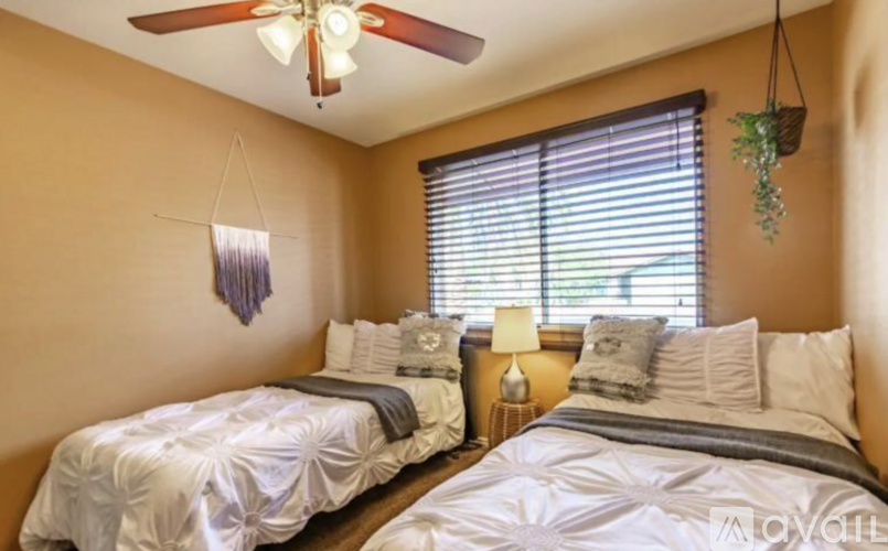 A bedroom with two beds and a ceiling fan.