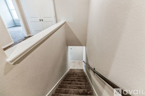A stairway with a carpeted runner and white walls.