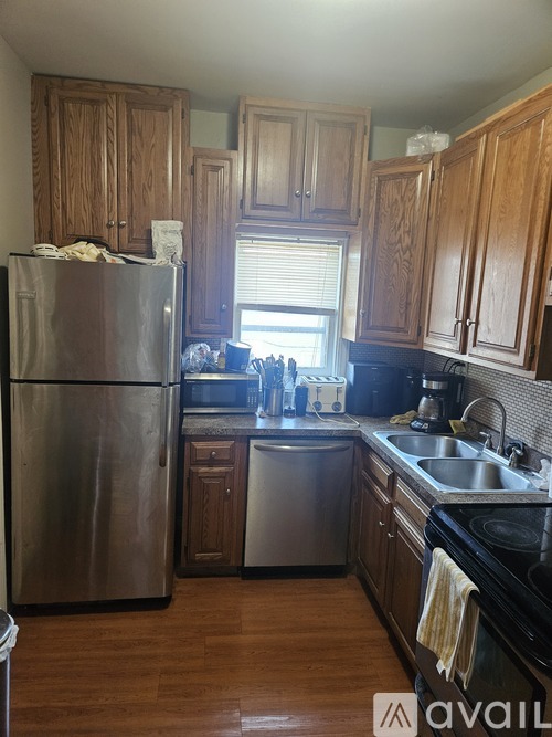 A kitchen with wooden cabinets and a stainless steel refrigerator.