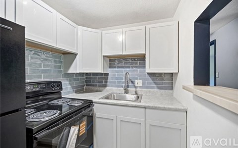 A kitchen with white cabinets and a black stove top oven.