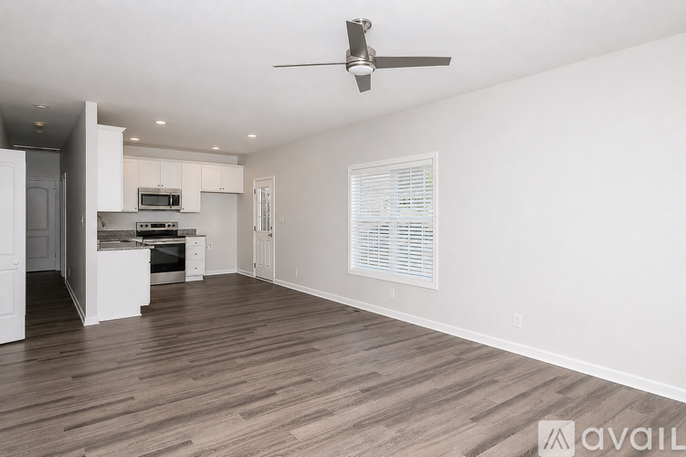A spacious room with wooden flooring and a ceiling fan.