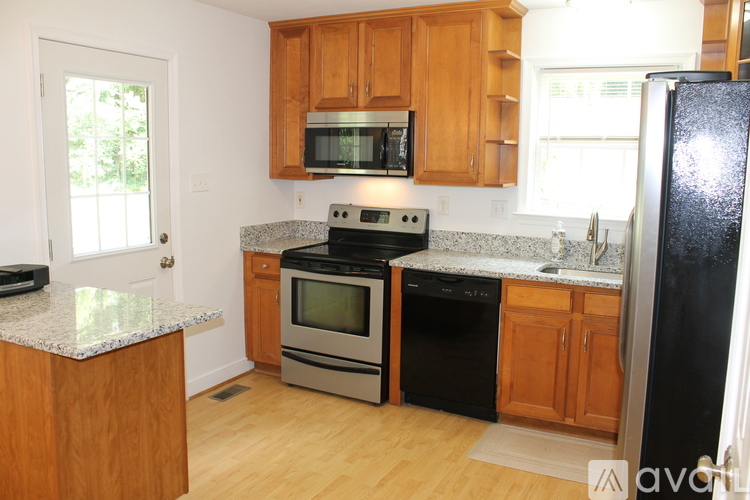 A kitchen with wooden cabinets and a black refrigerator.