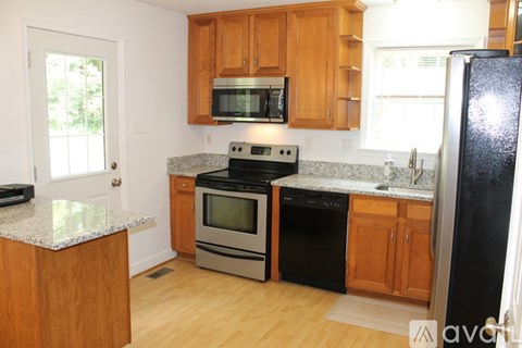 A kitchen with wooden cabinets and a black refrigerator.