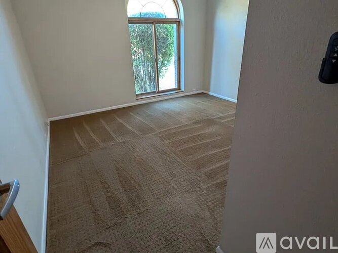 A room with a carpeted floor and a door leading to a balcony.