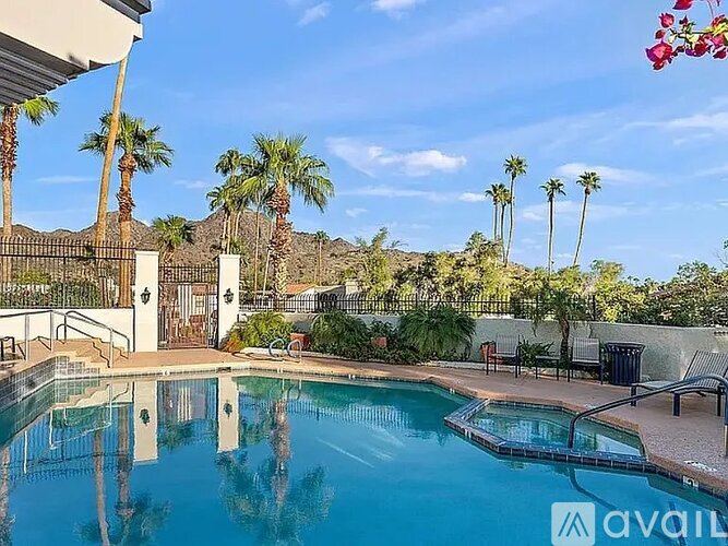 A pool surrounded by palm trees and a mountain in the background.