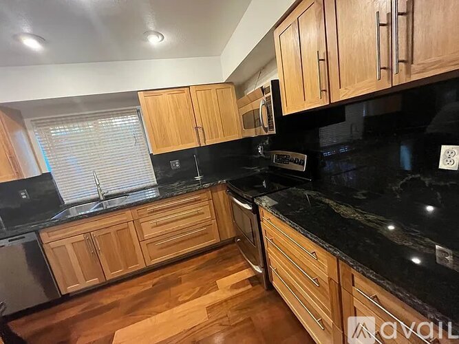 A kitchen with wooden cabinets and black countertops.